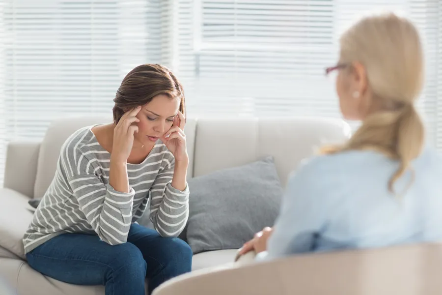 illustrasjon av fortvilet pasient som sitter i en sofa med behandleren på den andre siden