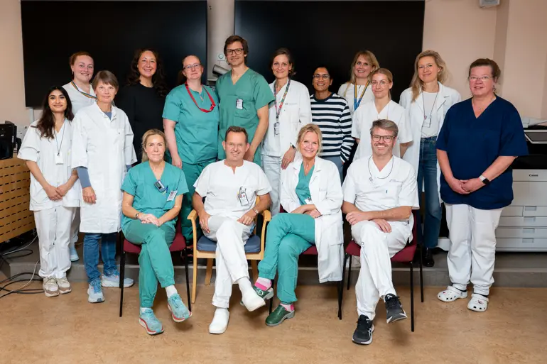Hele cranio facialt team i et gruppebilde. Fire sitter på stoler foran resten som står bak. Alle smiler mot kameraet og de fleste har på seg grønt eller hvitt.