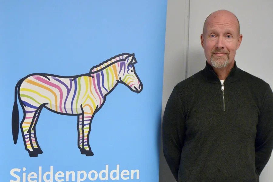 Tom Rune foran Sjeldenpodden-poster