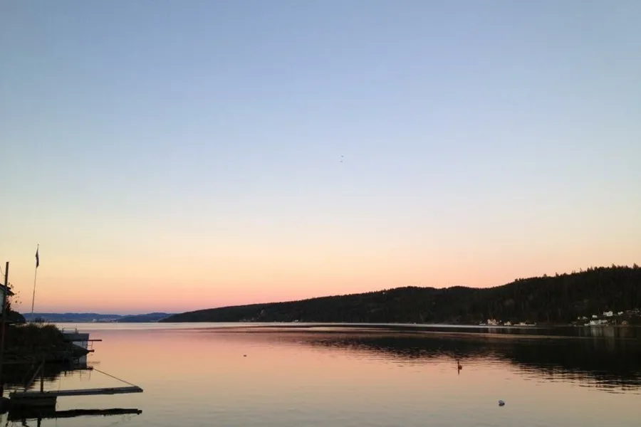 En vannmasse med trær og åser i bakgrunnen