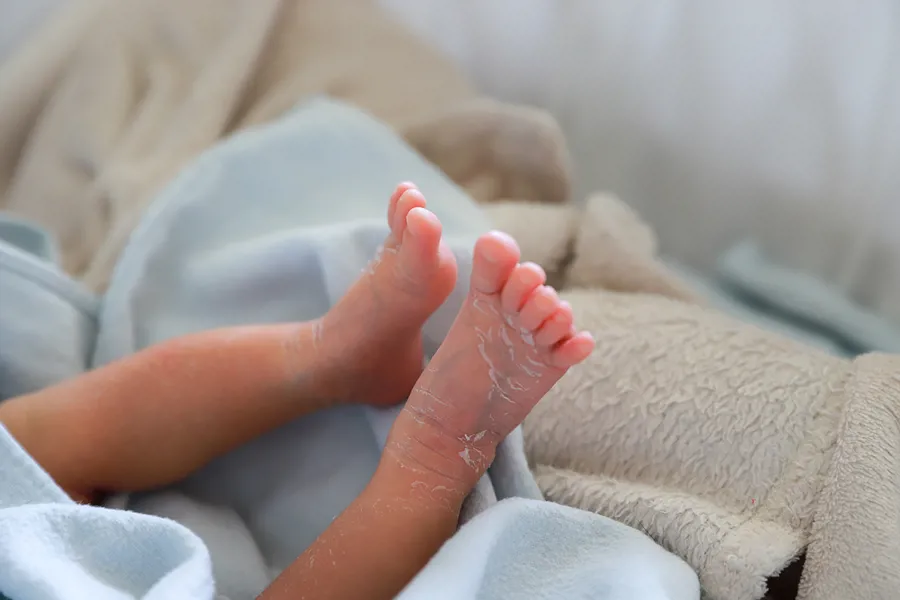 To ben og føtter med tørr hud fra en nyfødt baby strekker seg ut