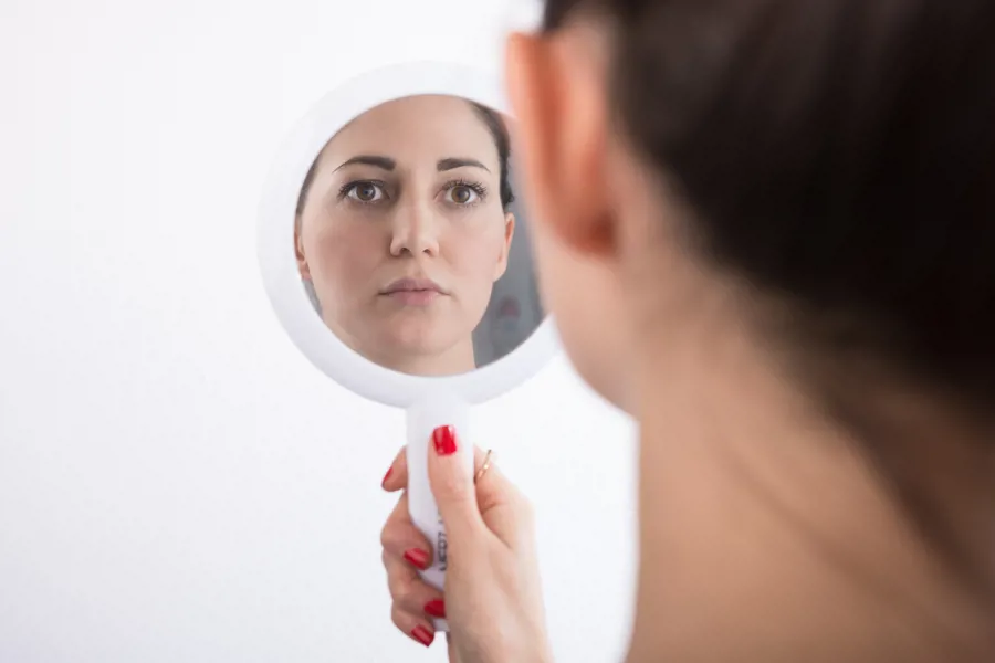 Kvinne ser på speilbildet sitt