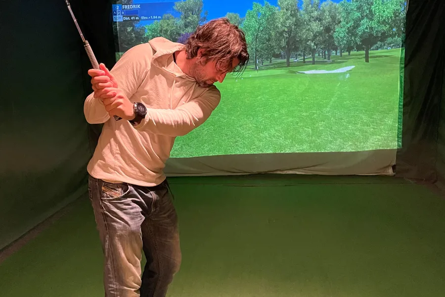 Foto av mann som spiller golf i golfsimulator
