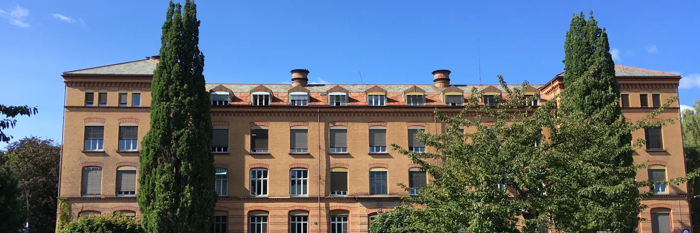 En stor murbygning med trær foran seg