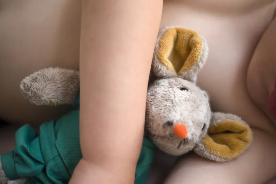 Sovende barn med sykehusmaskoten Rasmus i armkroken