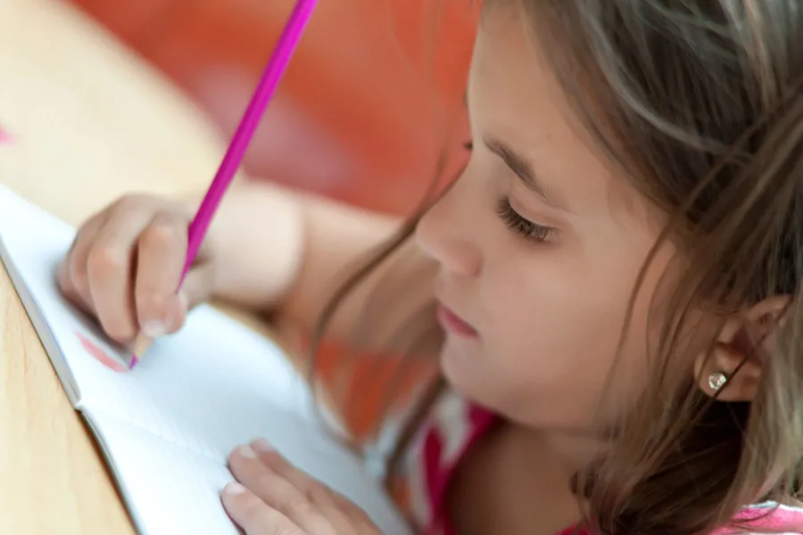 En ung jente som skriver på et stykke papir.