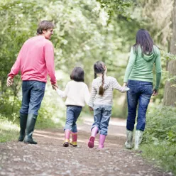 To voksne og to barn som går på tur i skogen
