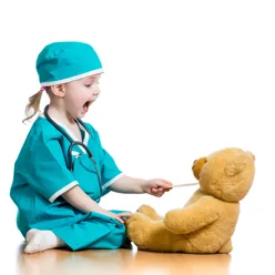 En ung jente i grønne sykehusklær som leker doktor med en bamse