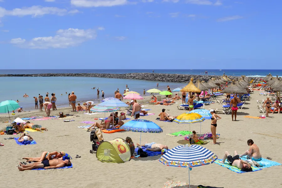 Bilde av turister på stranden og parasoller