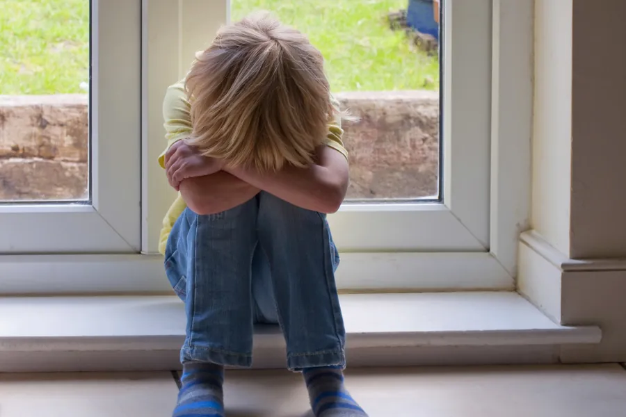 Gutt sitter med hodet bøyd ned i armene