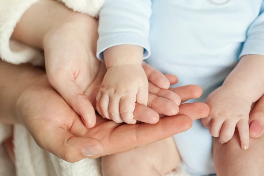 Babyhender som holder i voksenhender