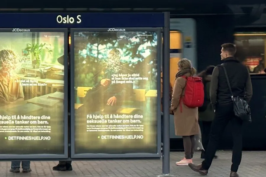 Folk som står ved siden av et skilt